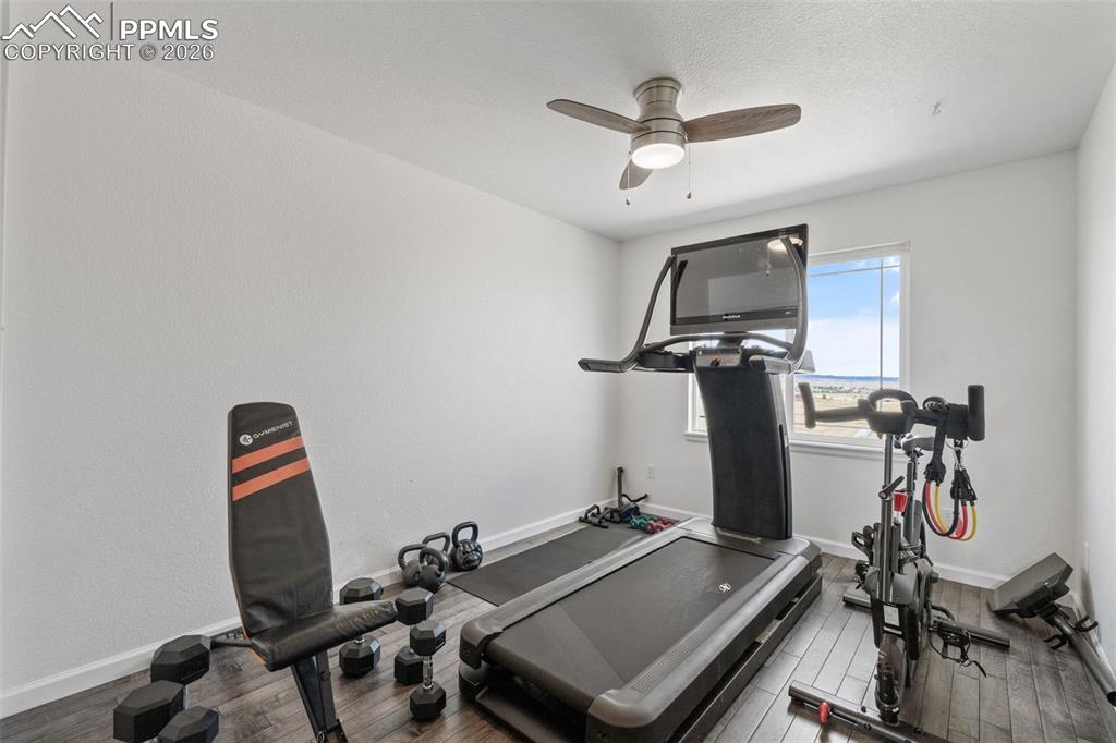Image 28 of 47: Exercise area featuring dark wood-style floors and a ceiling fan
