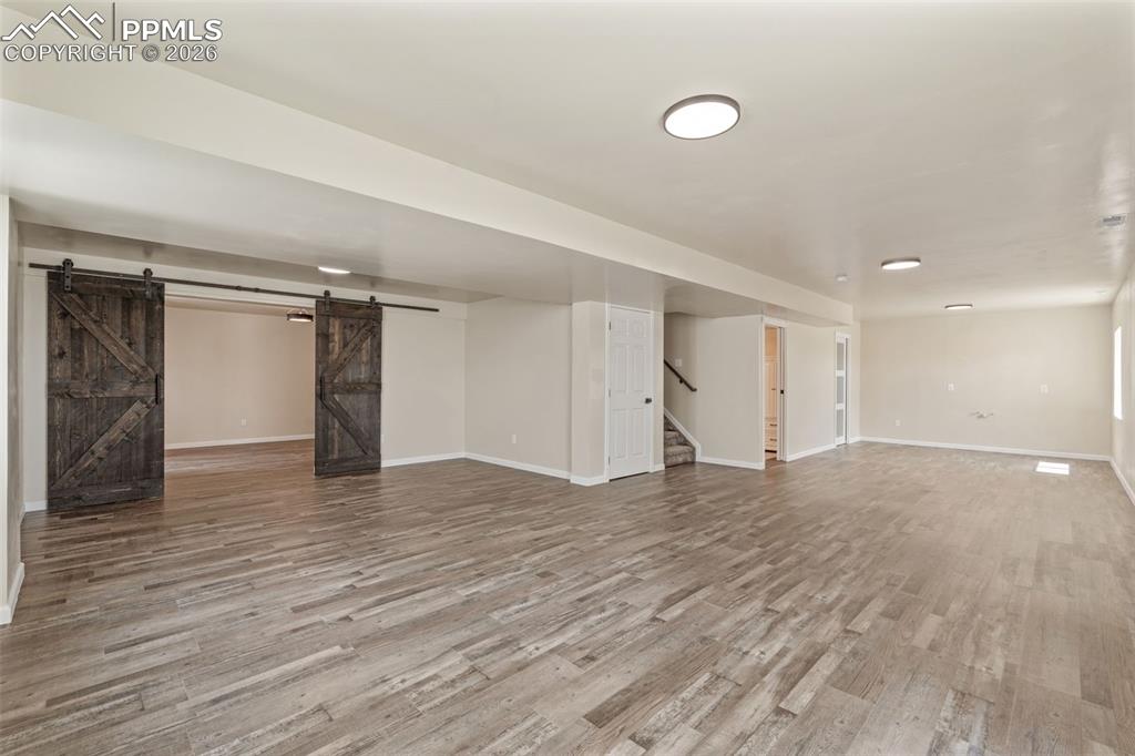 Image 31 of 47: Finished basement featuring a barn door and light wood-type flooring