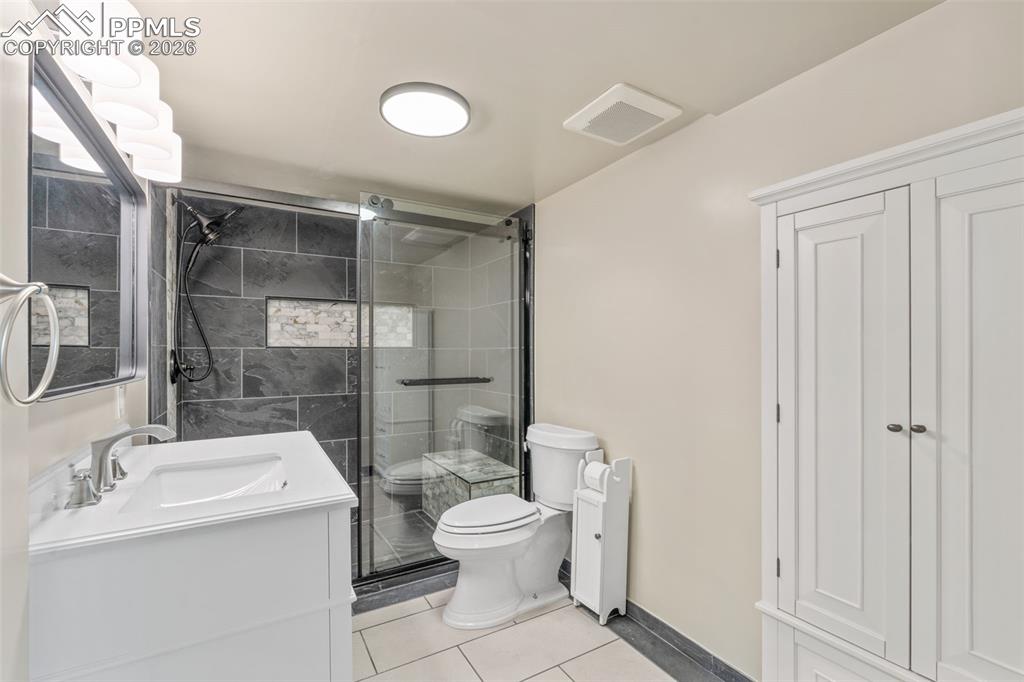 Image 32 of 47: Full bath featuring a shower stall, vanity, and light tile patterned floors