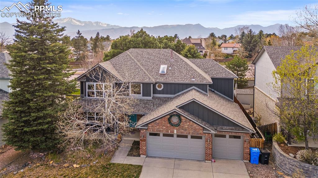 Image 35 of 35: View of front of home with a shingled roof, a mountain view, concrete drive
