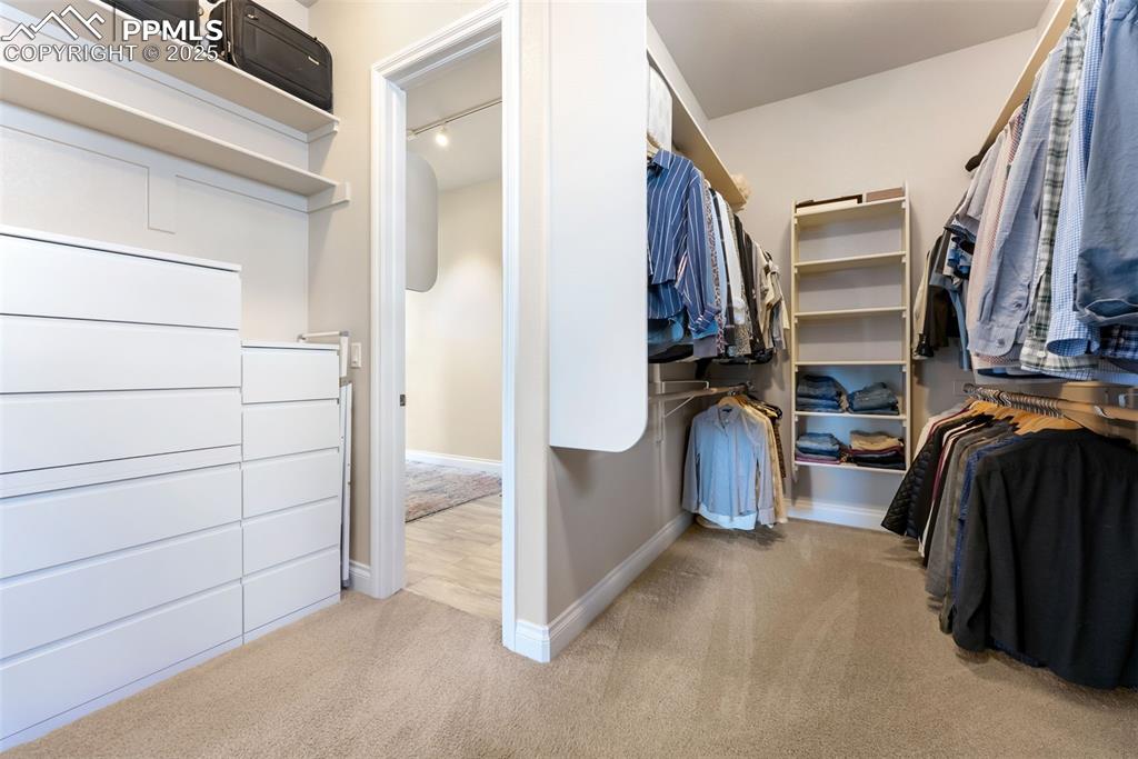 Image 25 of 50: Large walk-in closet with built-in shelves, racks, and drawers