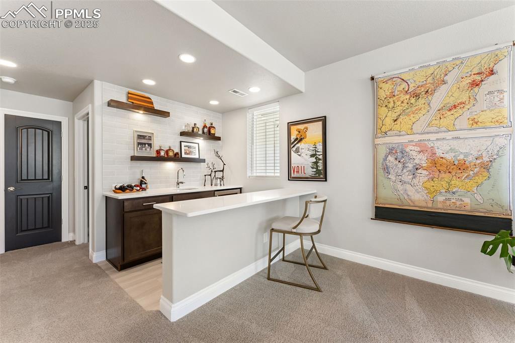 Image 35 of 50: Enjoy a snack or drink with others at this wet bar. Overhanging counter for