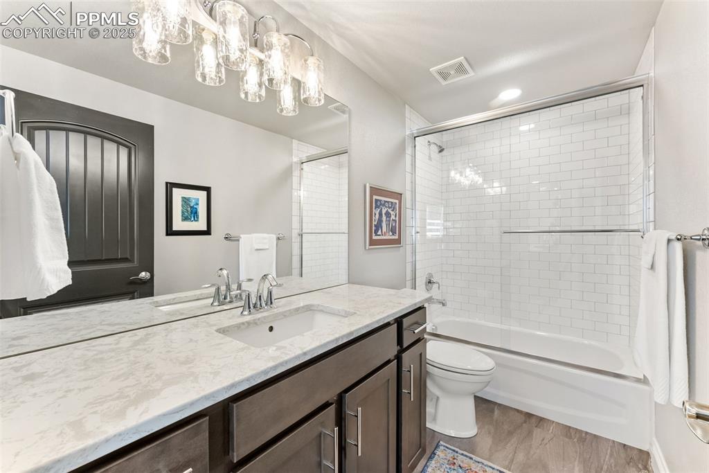 Image 42 of 50: Basement level bathroom with quartz countertops and white subway tile showe