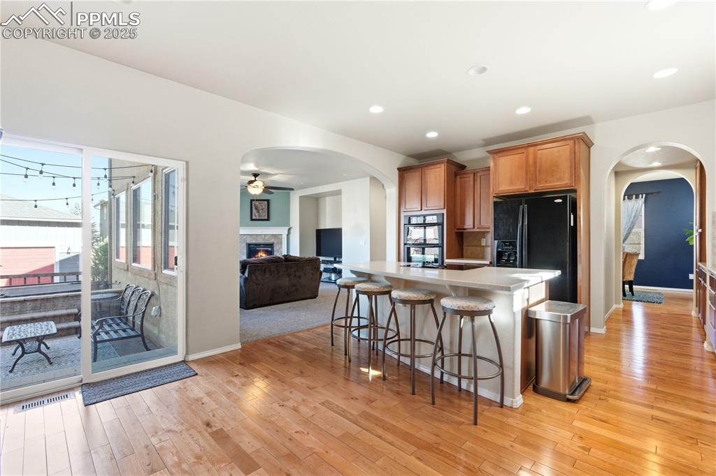 Image 12 of 42: Kitchen featuring arched walkways, brown cabinetry, a breakfast bar area, a