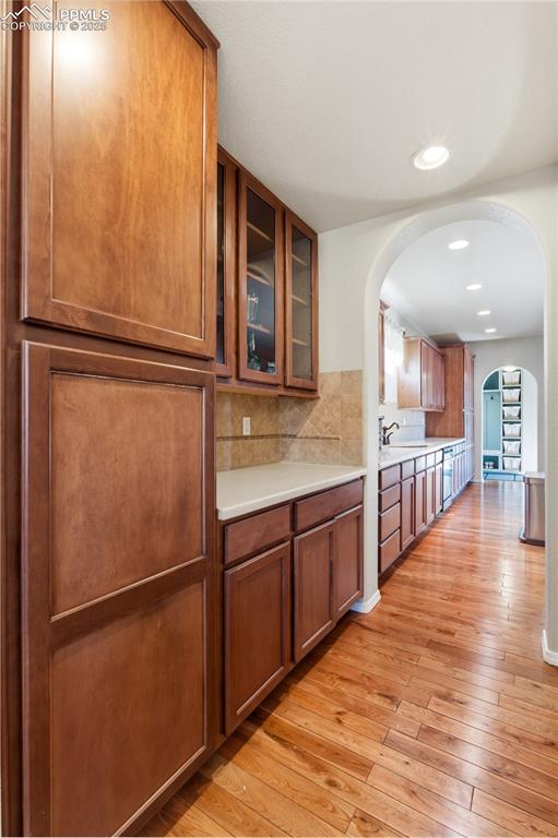 Image 13 of 42: Kitchen featuring arched walkways, glass insert cabinets, brown cabinetry, 