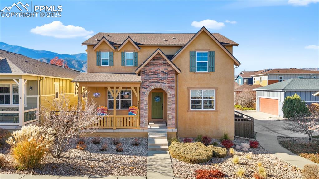 Image 2 of 42: Traditional home featuring stucco siding, a shingled roof, covered porch, a