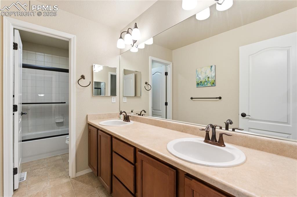 Image 24 of 42: Bathroom with double vanity, light tile patterned floors, and combined bath