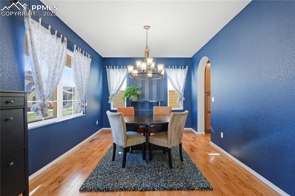 Image 3 of 42: Dining room with a textured wall, light wood-style floors, arched walkways,