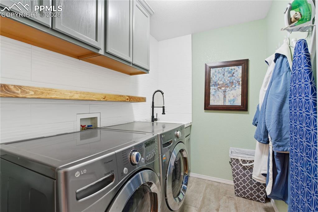 Image 31 of 42: Laundry area with cabinet space, separate washer and dryer, and light tile 