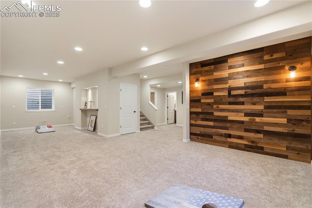 Image 32 of 42: Finished basement with light colored carpet, recessed lighting, wood walls,