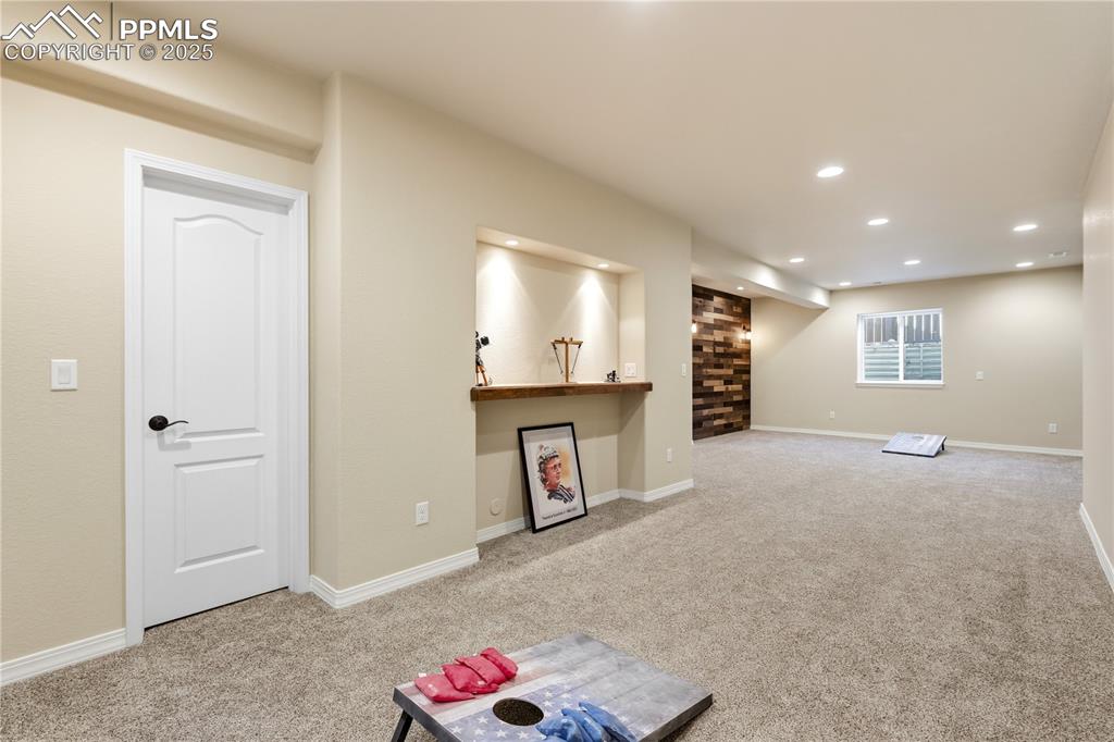 Image 33 of 42: Below grade area with light colored carpet, a bar, and recessed lighting
