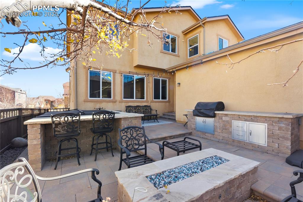 Image 38 of 42: View of patio with an outdoor fire pit and exterior kitchen