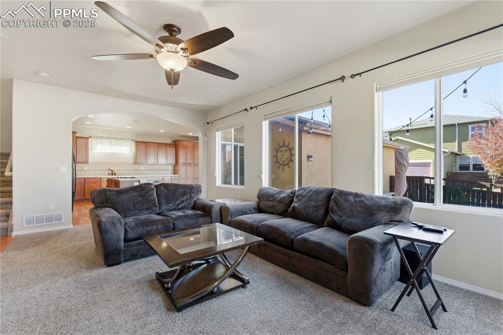 Image 8 of 42: Living room with plenty of natural light, light colored carpet, arched walk
