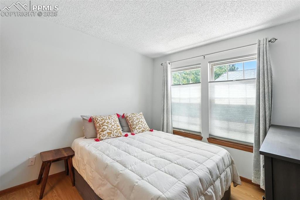 Image 10 of 25: Bedroom featuring a textured ceiling and light wood finished floors