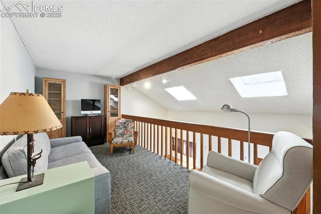 Image 13 of 25: Living area with a skylight, a textured ceiling, and carpet