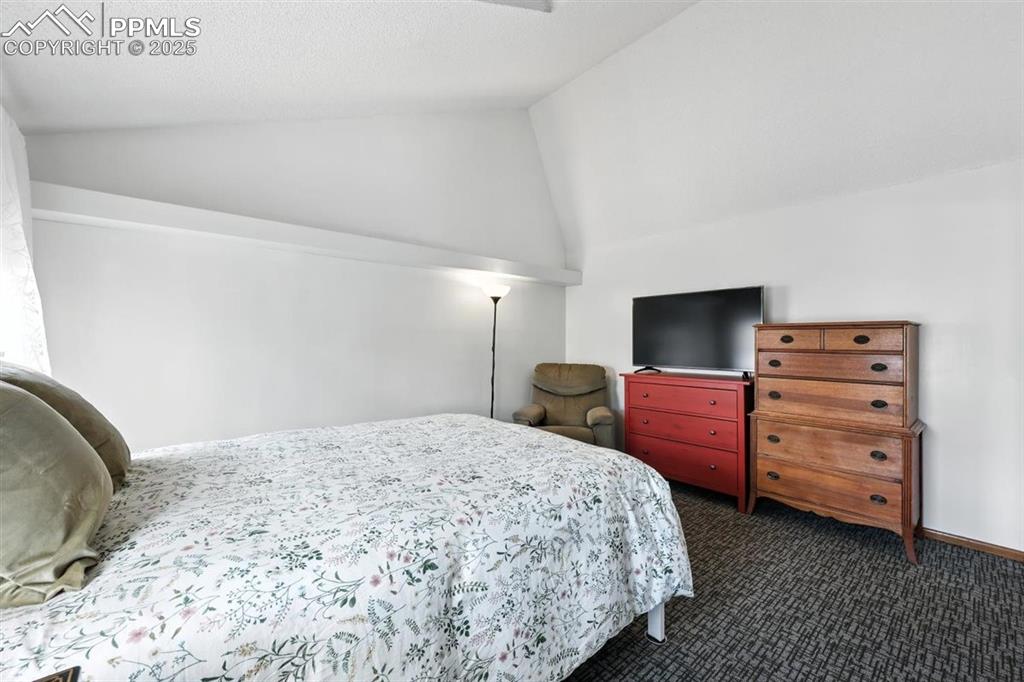 Image 16 of 25: Bedroom with lofted ceiling and carpet floors