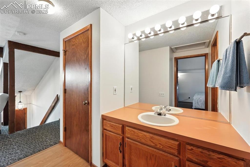 Image 17 of 25: Bathroom with a textured ceiling, ensuite bathroom, wood finished floors, a