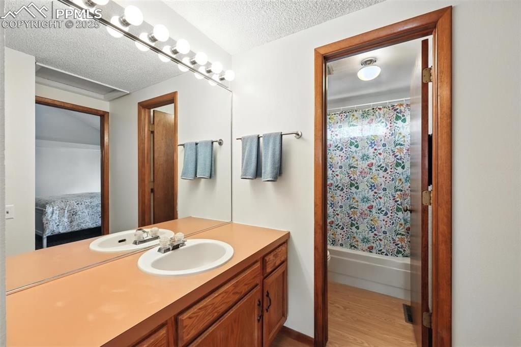 Image 18 of 25: Ensuite bathroom featuring vanity, wood finished floors, a textured ceiling