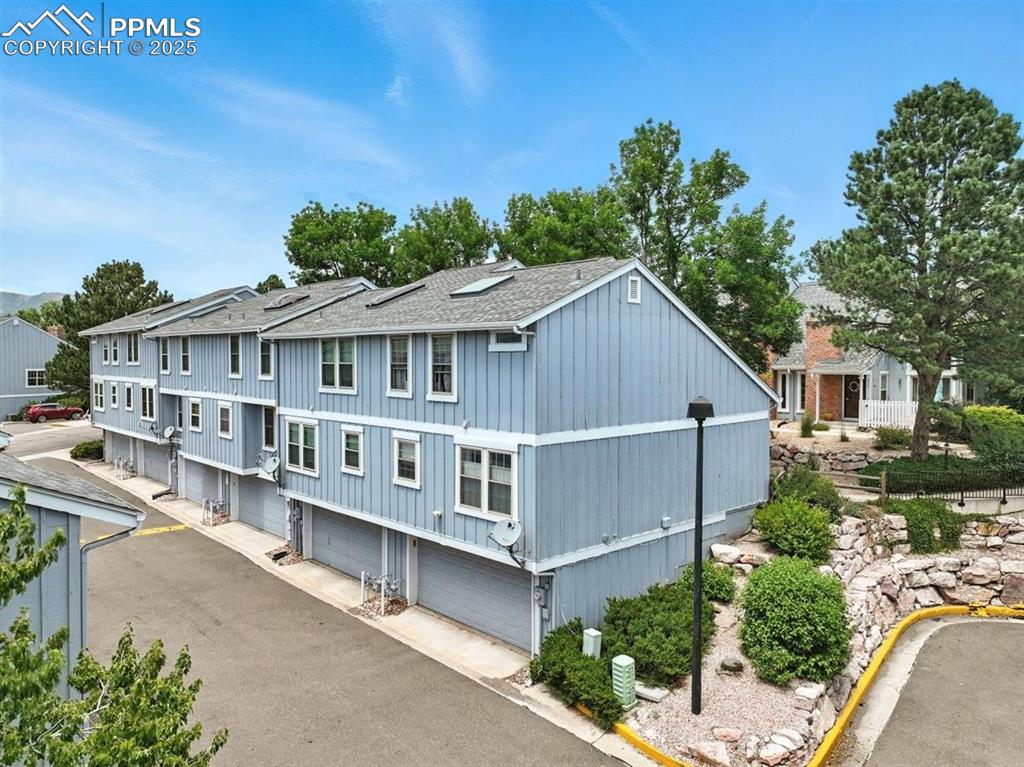 Image 21 of 25: View of front of home with a shingled roof, a garage, and a residential vie