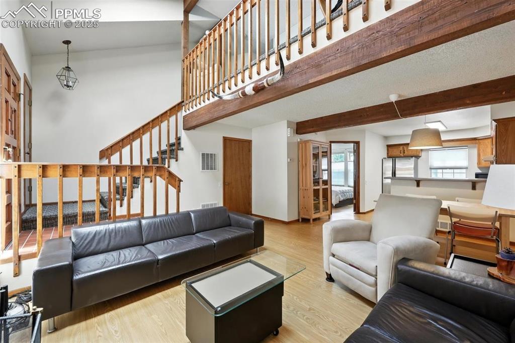 Image 4 of 25: Living room featuring stairs, wood finished floors, and beamed ceiling