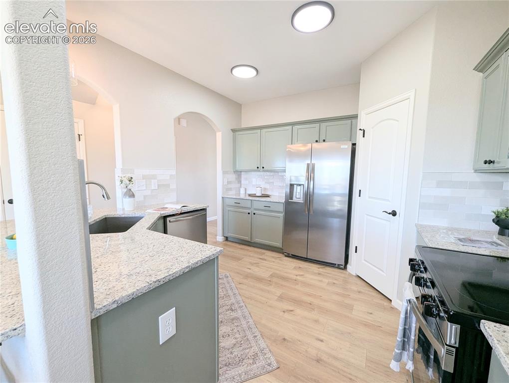 Image 13 of 49: Modern kitchen featuring stainless steel appliances, light green cabinetry,