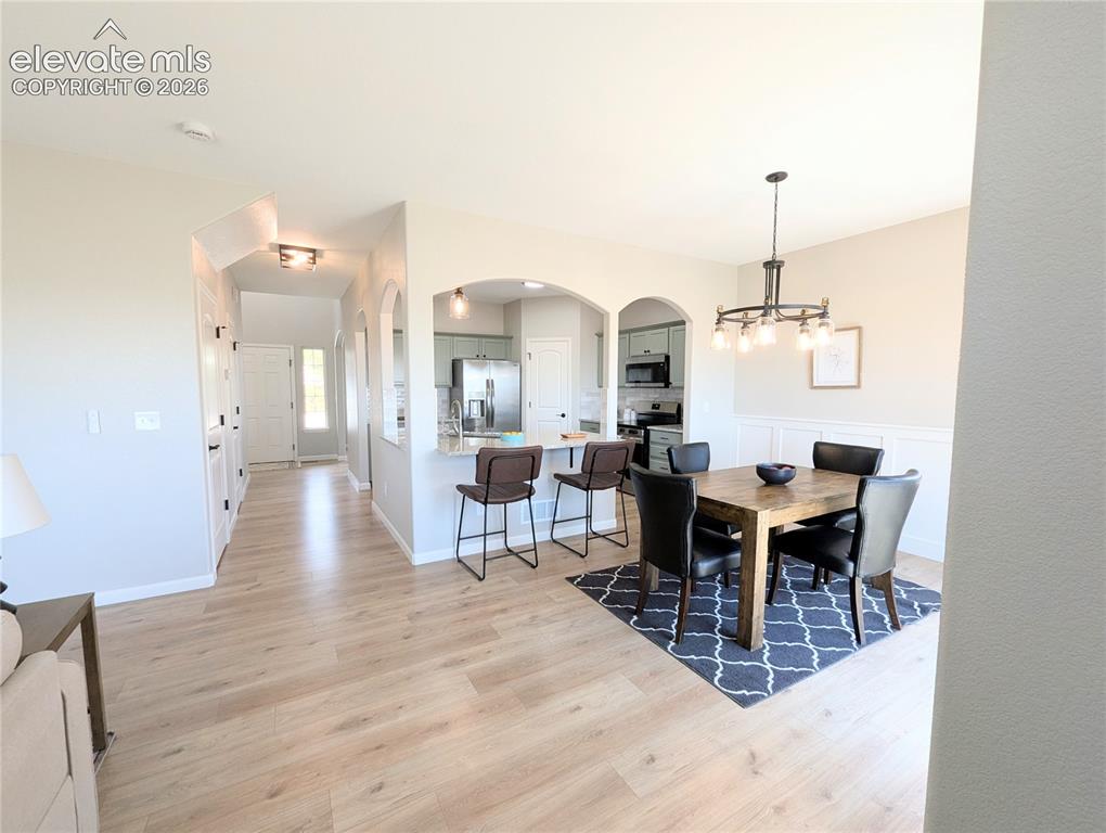 Image 16 of 49: Dining area featuring a contemporary chandelier, board and batten wall deta