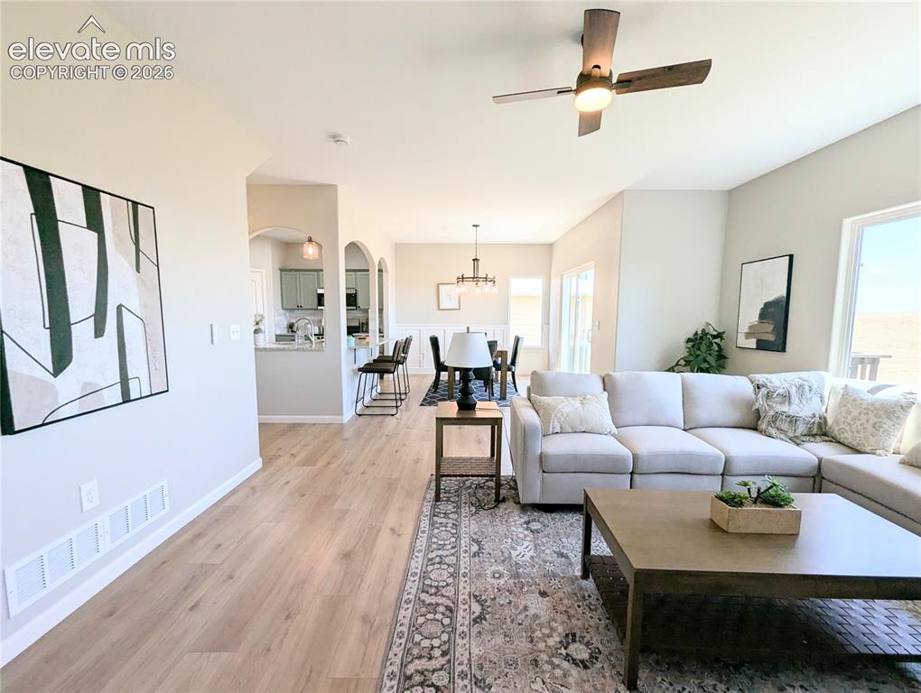 Image 20 of 49: Open concept dining area featuring a linear chandelier, wainscoting, and wo