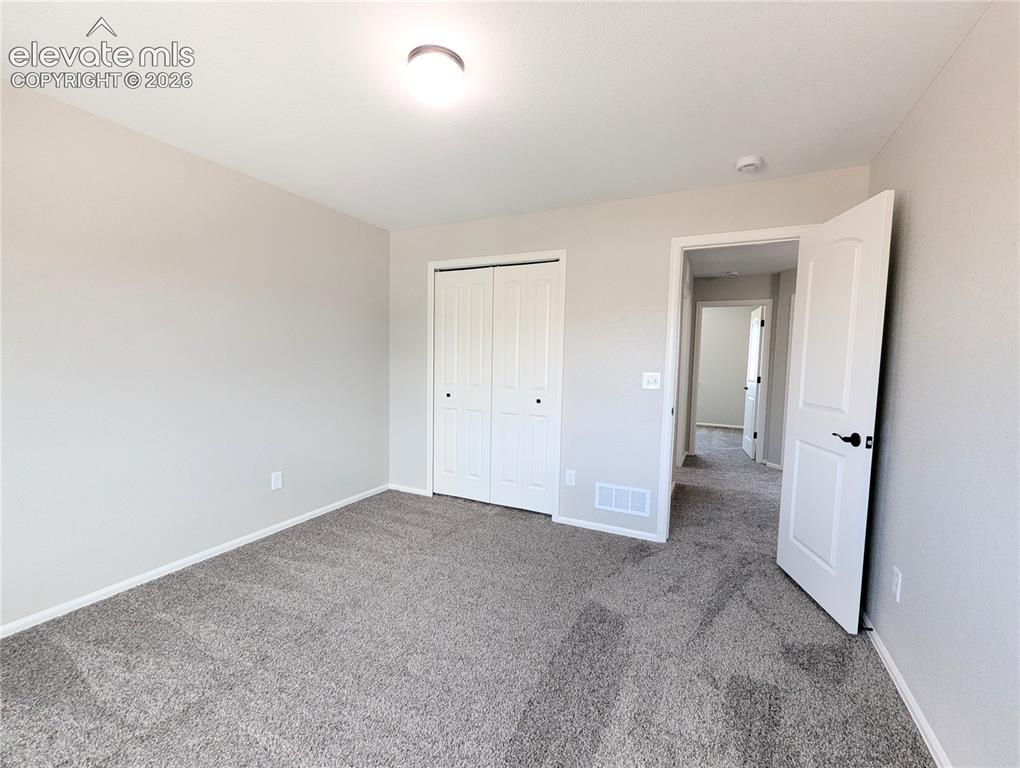 Image 37 of 49: Room featuring neutral wall tones and dark patterned carpeting