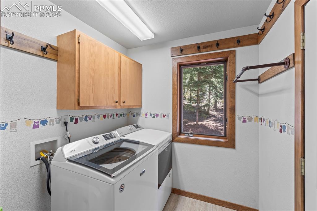 Image 13 of 49: Laundry room with cabinet space, washer and dryer, and light wood-style flo