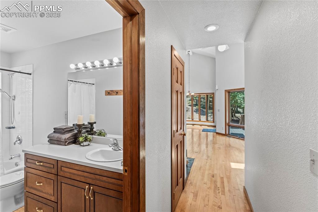 Image 15 of 49: Full bath with vanity, wood finished floors, a textured wall, and shower /