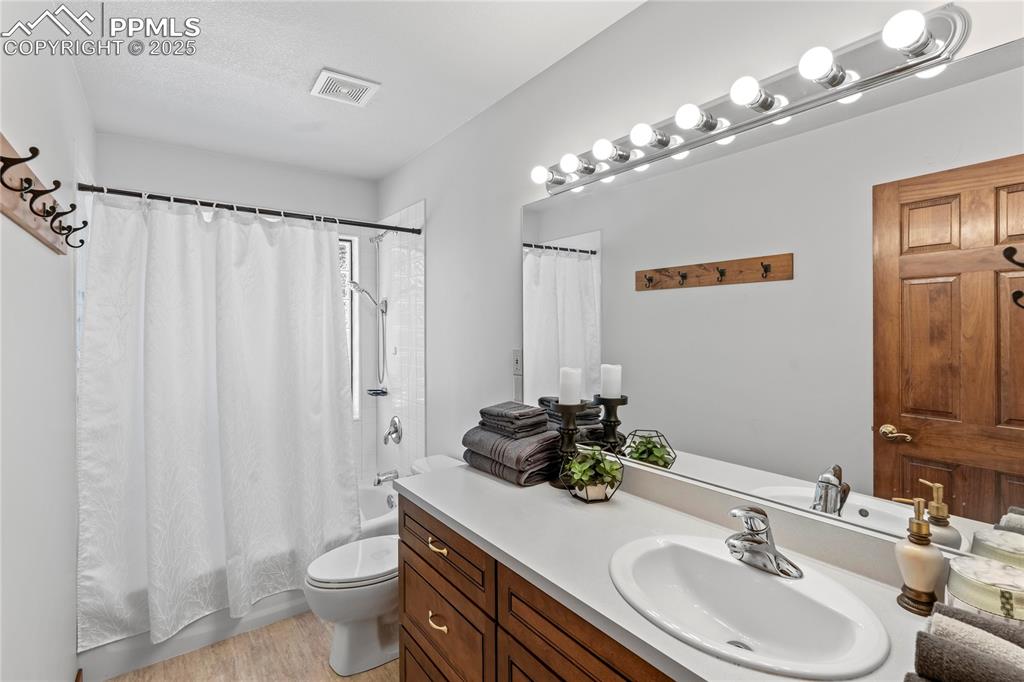 Image 16 of 49: Full bathroom featuring vanity, shower / bath combo, and wood finished floo