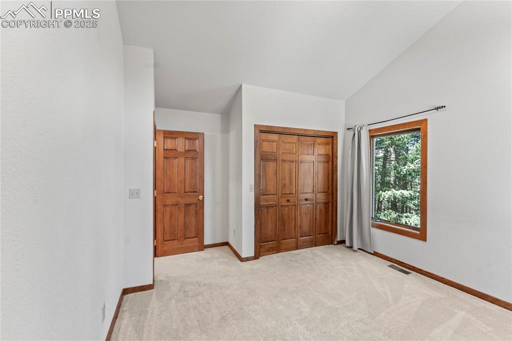 Image 18 of 49: Unfurnished bedroom with light carpet, a closet, and lofted ceiling