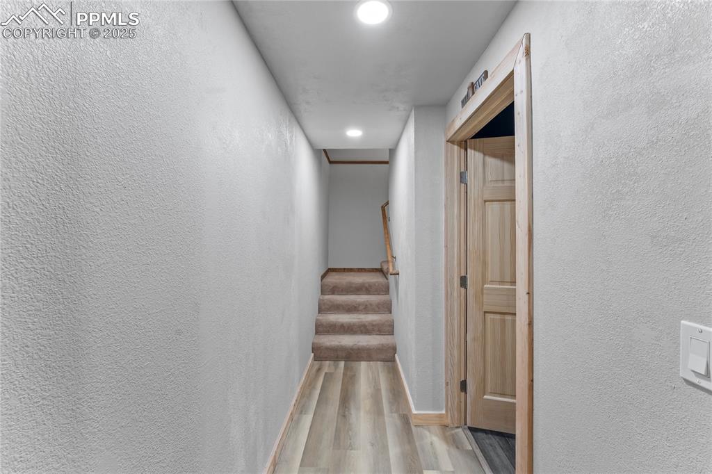 Image 25 of 49: Hallway featuring wood finished floors, a textured wall, stairway, and rece