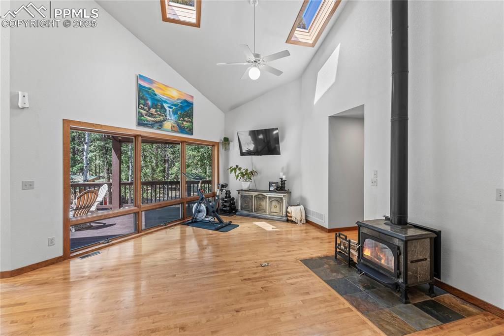 Image 3 of 49: Living area featuring high vaulted ceiling, wood finished floors, a wood st