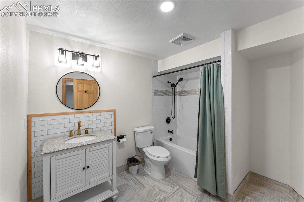 Image 31 of 49: Bathroom with vanity and shower / bath combo with shower curtain