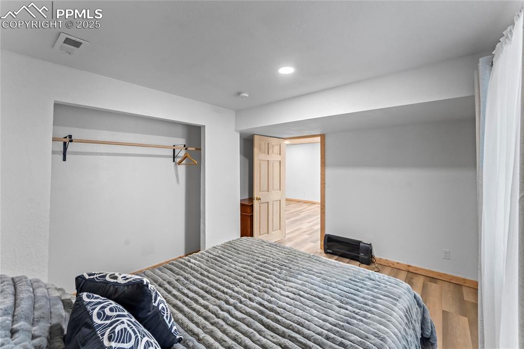 Image 37 of 49: Bedroom with wood finished floors, a closet, and recessed lighting