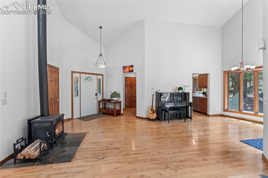 Image 5 of 49: Entryway featuring high vaulted ceiling, a wood stove, a chandelier, and li