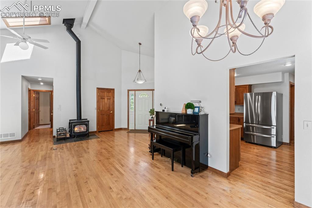Image 6 of 49: Living area featuring a wood stove, beam ceiling, light wood-style flooring
