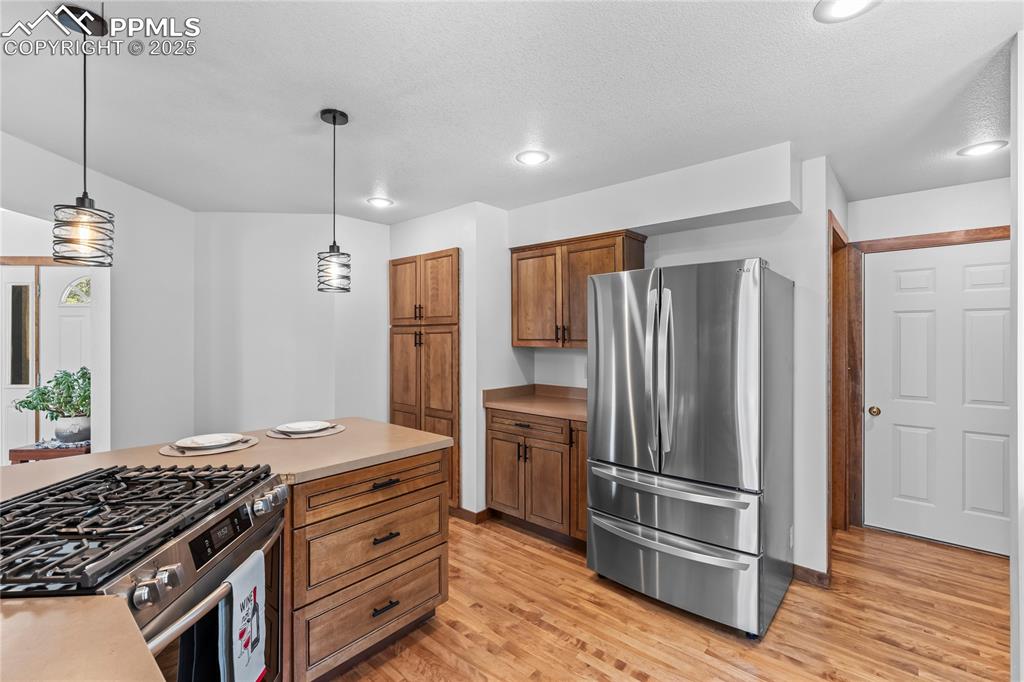 Image 9 of 49: Kitchen with appliances with stainless steel finishes, light wood-style flo