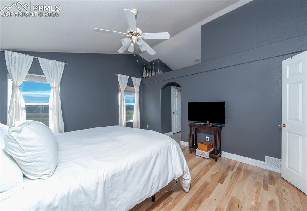 Image 10 of 50: Primary Bedroom featuring lofted ceiling, light wood finished floors, a cei