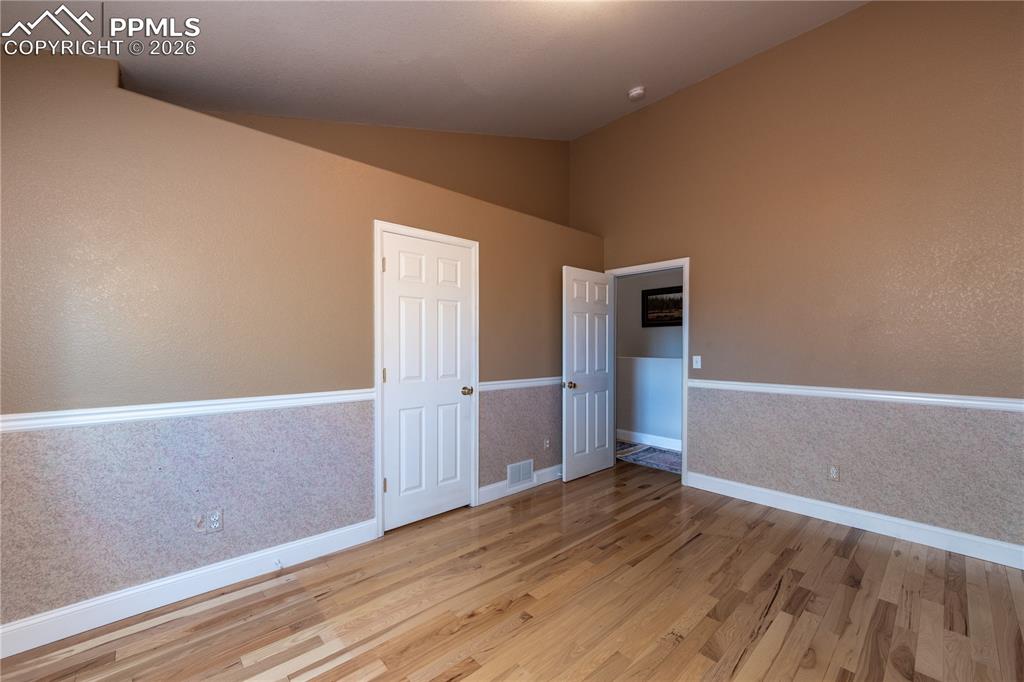 Image 17 of 50: Main-level Bedroom featuring wood finished floors and vaulted ceiling