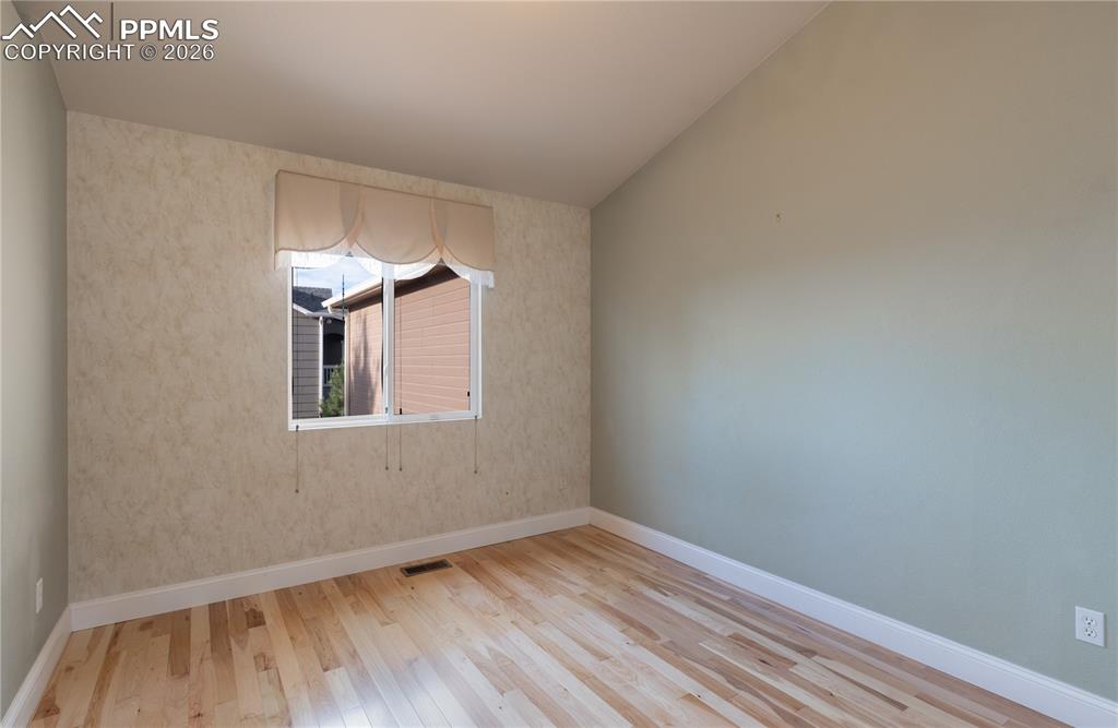 Image 19 of 50: Main-level Bedroom featuring wood finished floors and vaulted ceiling