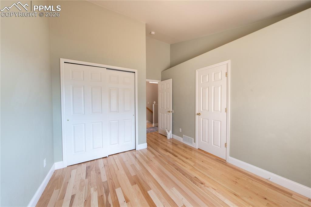 Image 20 of 50: Main-level Bedroom featuring wood finished floors and vaulted ceiling