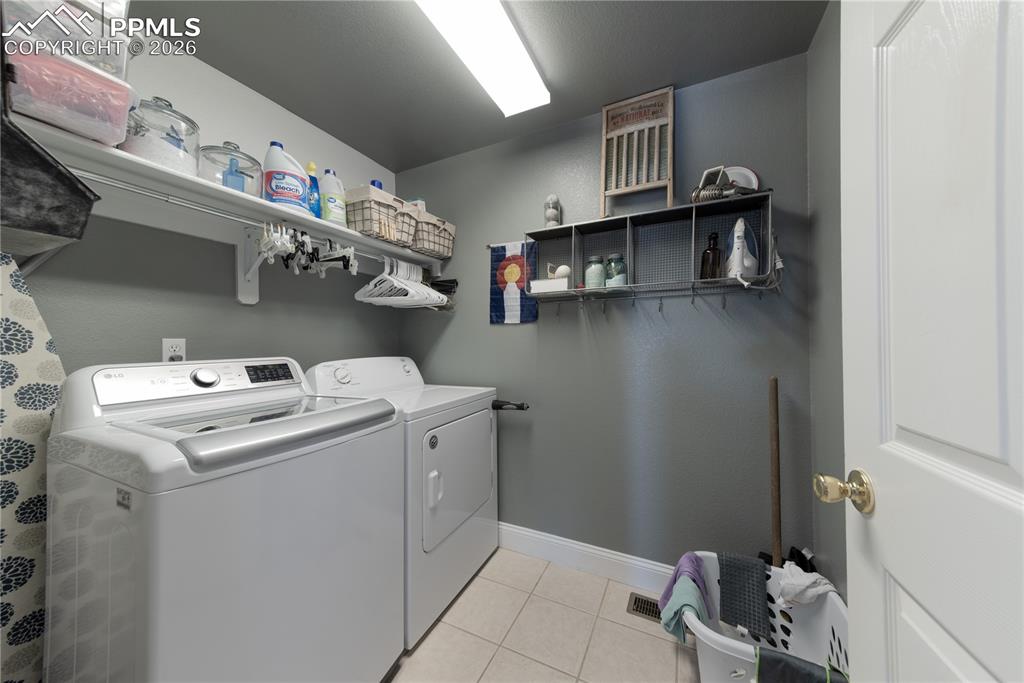 Image 24 of 50: Main-level Laundry area with washer and dryer and light tile patterned floo