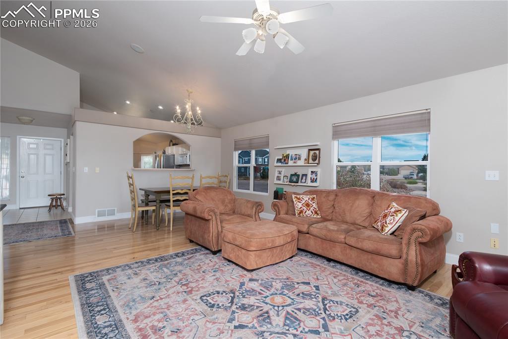 Image 8 of 50: Living room with lofted ceiling, a chandelier, and light wood finished floo