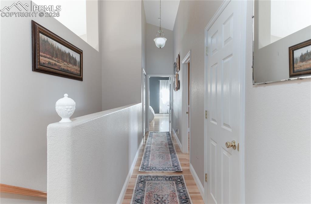 Image 9 of 50: Looking to Primary Bedroom - Hallway featuring high vaulted ceiling and lig