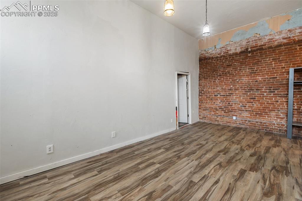 Image 21 of 34: Spare room with brick wall and wood finished floors