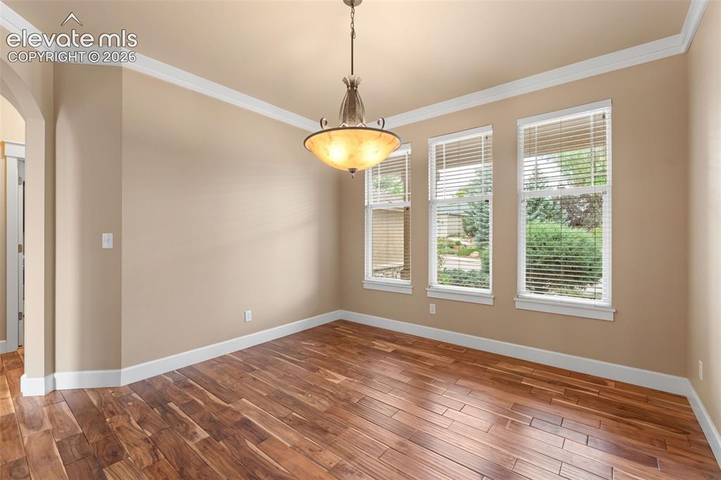 Image 15 of 48: Wood-finish flooring, crown molding, and a decorative ceiling fixture