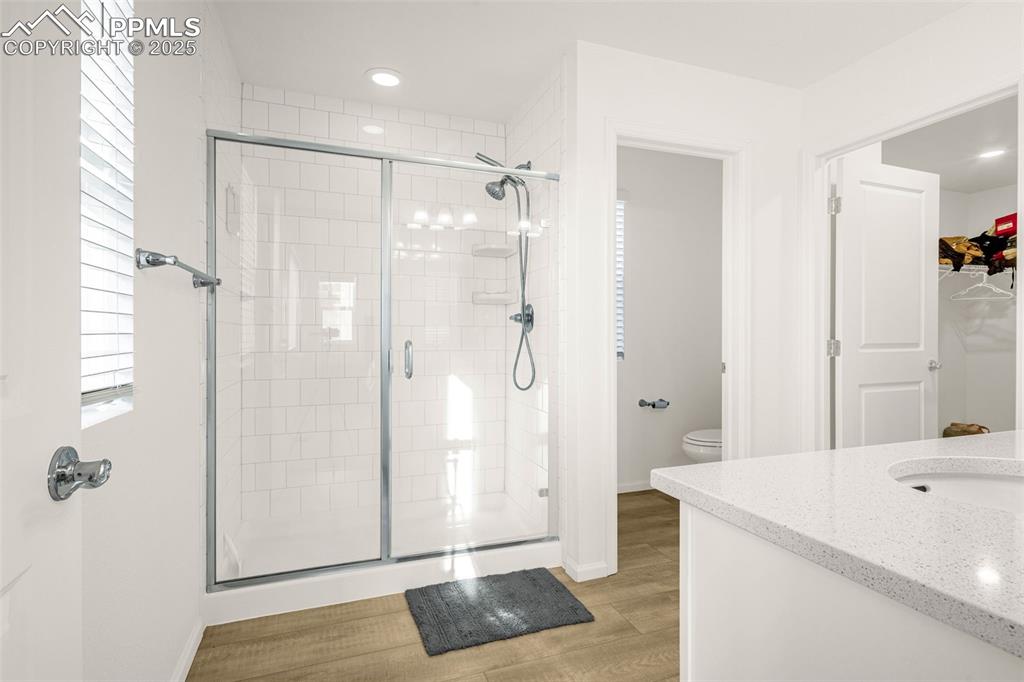 Image 11 of 38: Full bath with a shower stall, toilet, wood finished floors, and baseboards