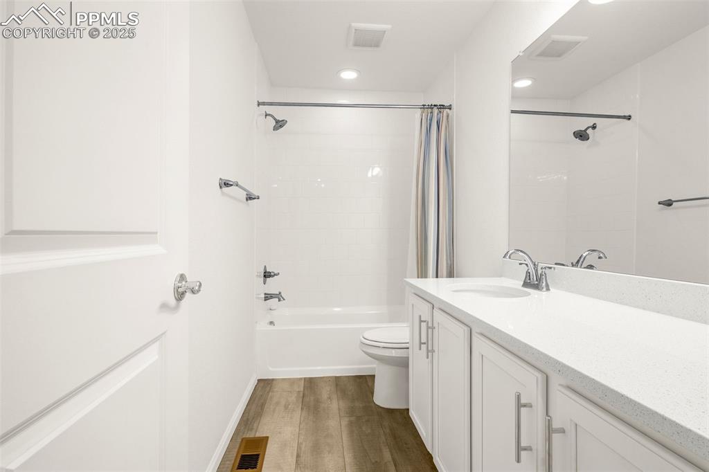 Image 23 of 38: Bathroom with wood finished floors, vanity, toilet, shower / bath combo wit